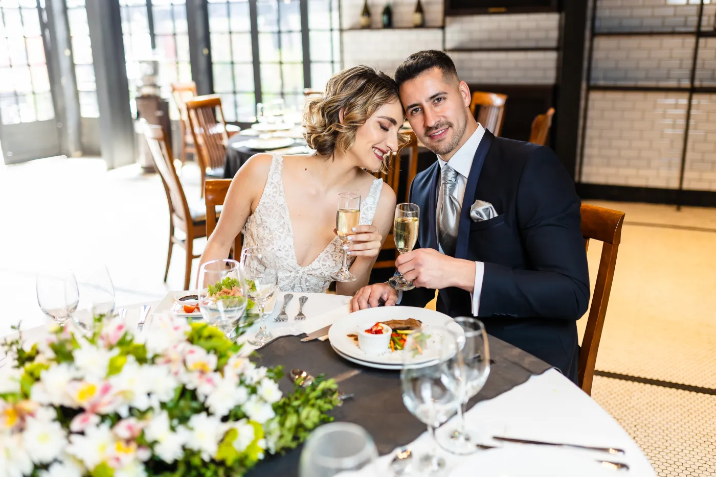 Novios en una mesa montada con flores y copas