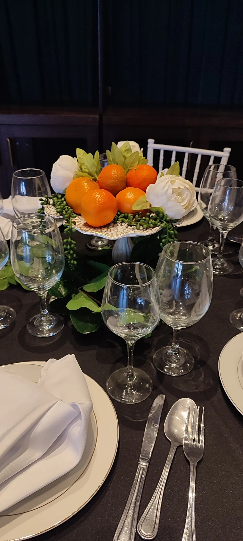 Montaje de mesa con vajilla, copas y decoración de frutas cítricas